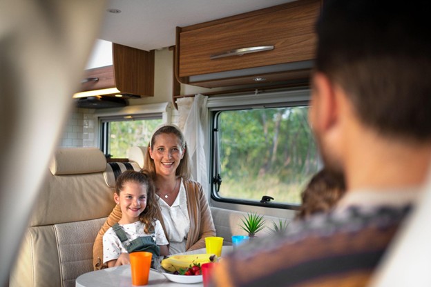 Smiling mother and daughter enjoying breakfast inside a modern RV with family, highlighting family-friendly RV travel and road trip lifestyle.